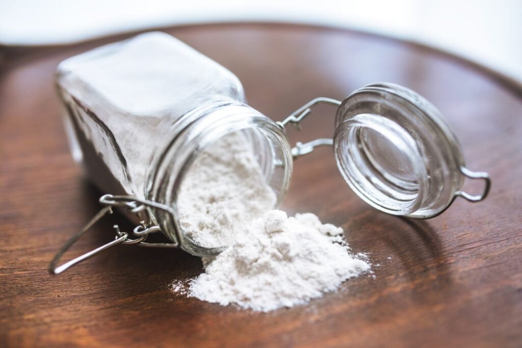 Oleochemicals & Bioenergy Derivatives Glass jar tipped over with white flour spilling onto a wooden surface, ideal for baking themes.