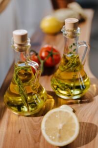 aerospace Close-up of herb-infused olive oil with fresh lemon and tomatoes on wooden surface.