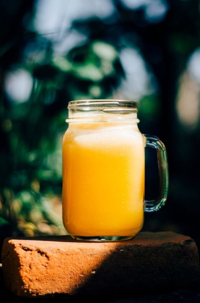 Oleochemicals & Bioenergy Derivatives Fresh orange juice in a mason jar on a red brick, captured outdoors in daylight.