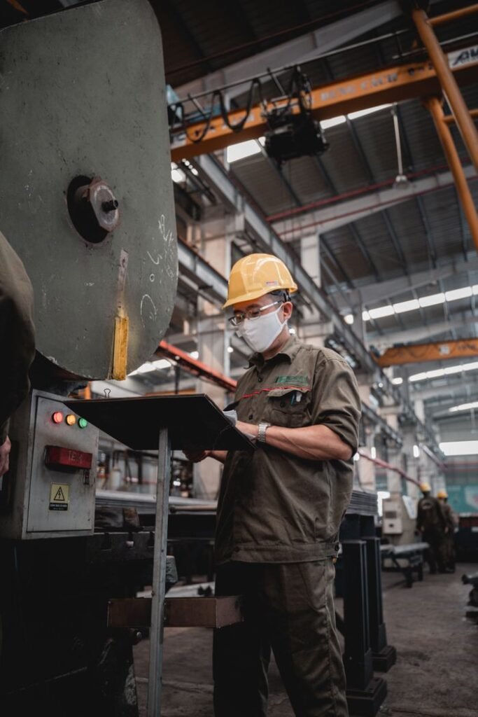 Sustainability Factory worker with safety gear checks machinery, ensuring industrial safety compliance.