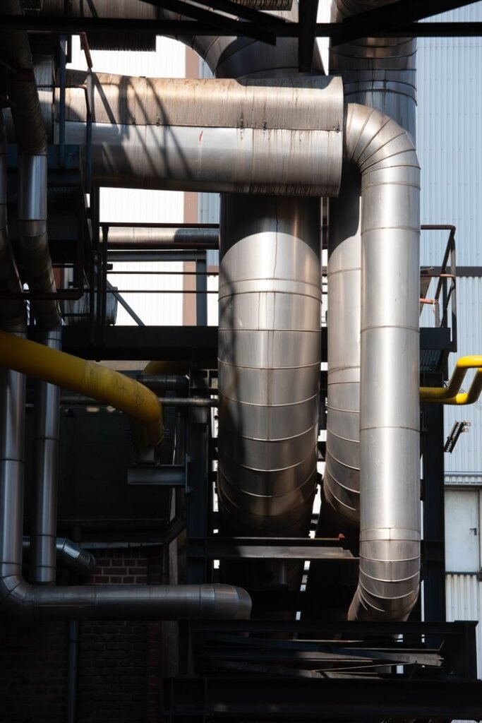 Sustainability Intricate network of stainless steel pipes in an industrial complex under sunlight.