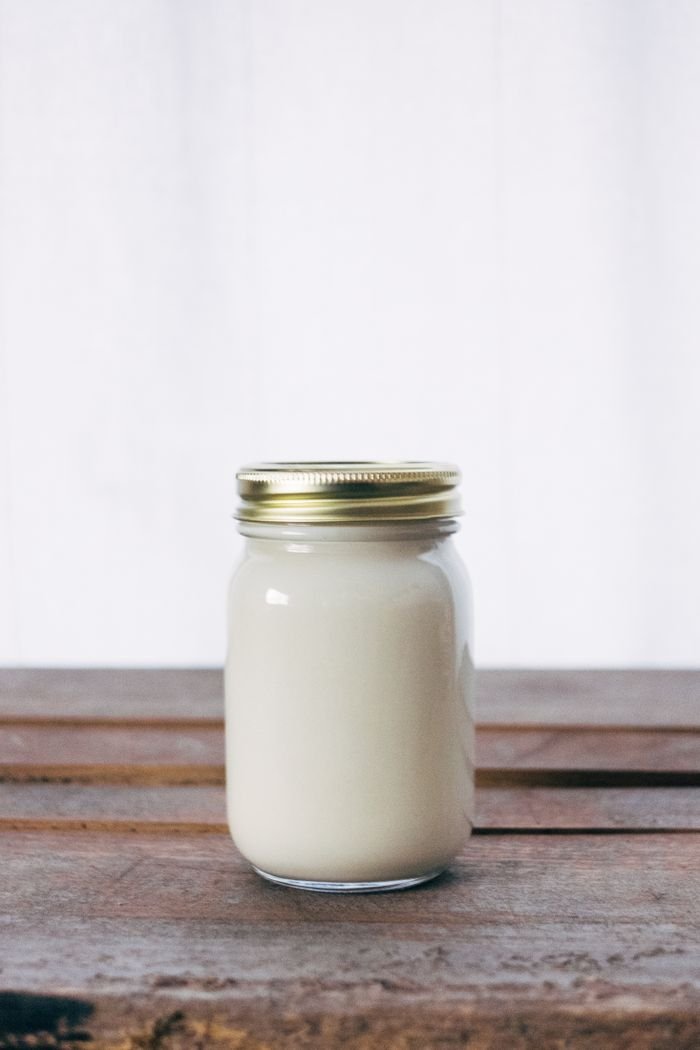Products A rustic glass jar filled with creamy yogurt, placed on a wooden table. Ideal for healthy food themes.