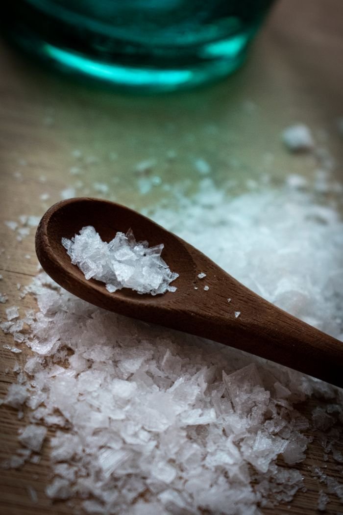 Oleochemicals & Bioenergy Derivatives Detailed view of coarse sea salt crystals on a wooden spoon, perfect for culinary themes.