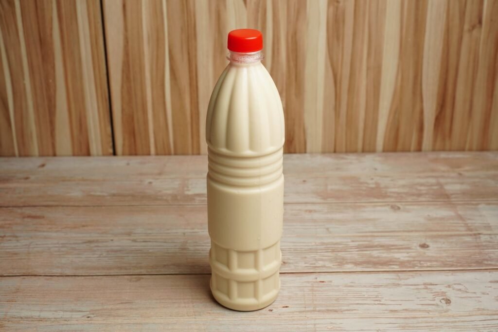 Oleochemicals & Bioenergy Derivatives Close-up of a plastic milk bottle with a red cap on a rustic wooden table with copy space.