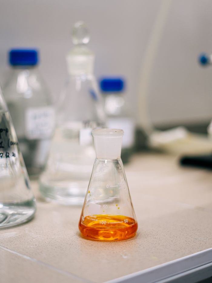 Products An Erlenmeyer flask containing orange liquid on a lab bench, surrounded by glassware.