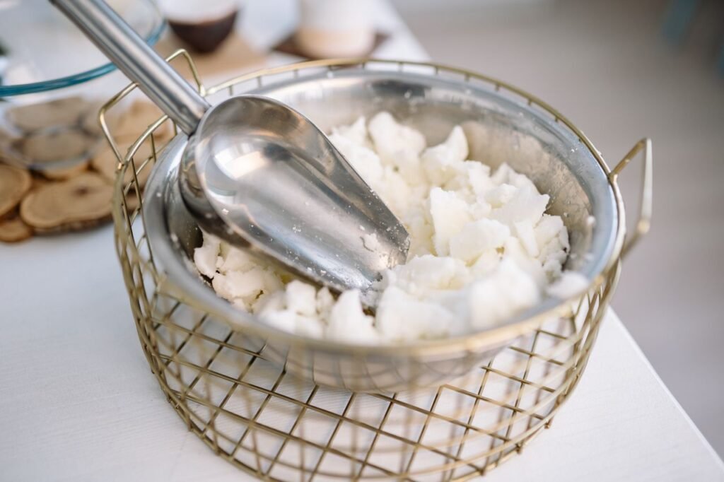 Palm Kernel Products Close-up of a stainless steel bowl filled with candle wax and a scooper, suitable for candle making.