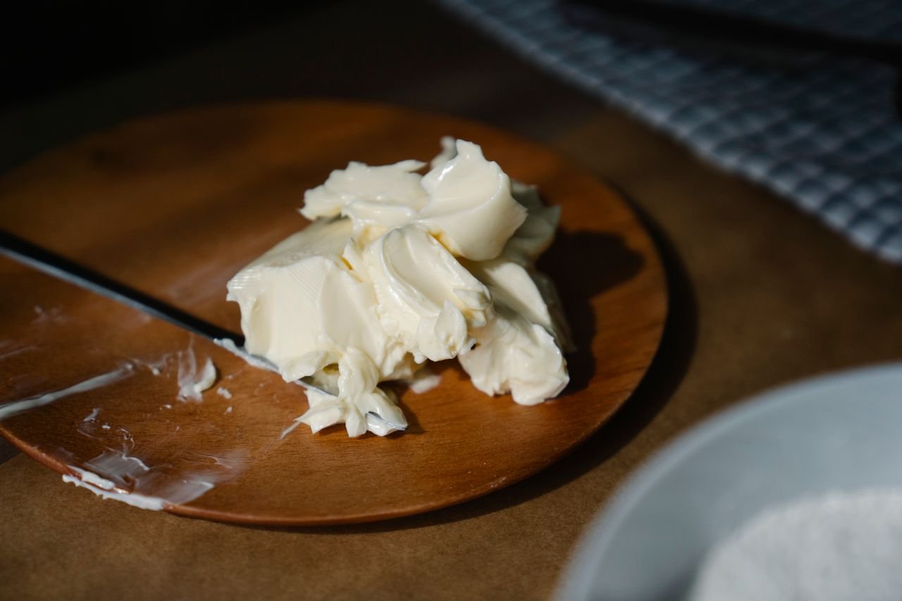 Products Aesthetic close-up of creamy butter on a wooden plate, perfect for culinary themes.