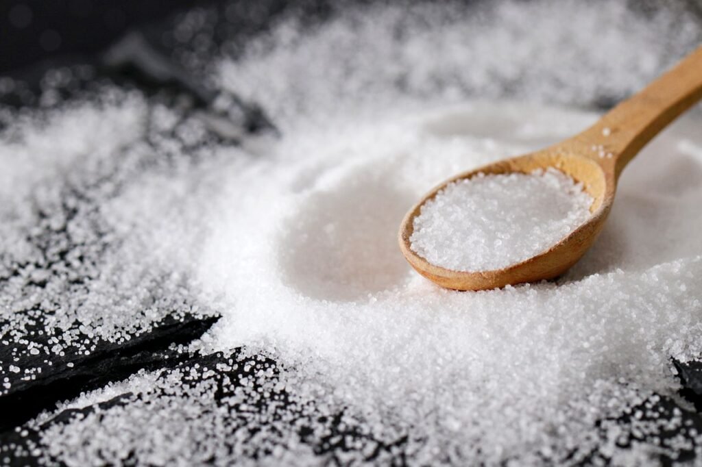 Oleochemicals & Bioenergy Derivatives A close-up view of fine sea salt in a wooden spoon, perfect for culinary uses.