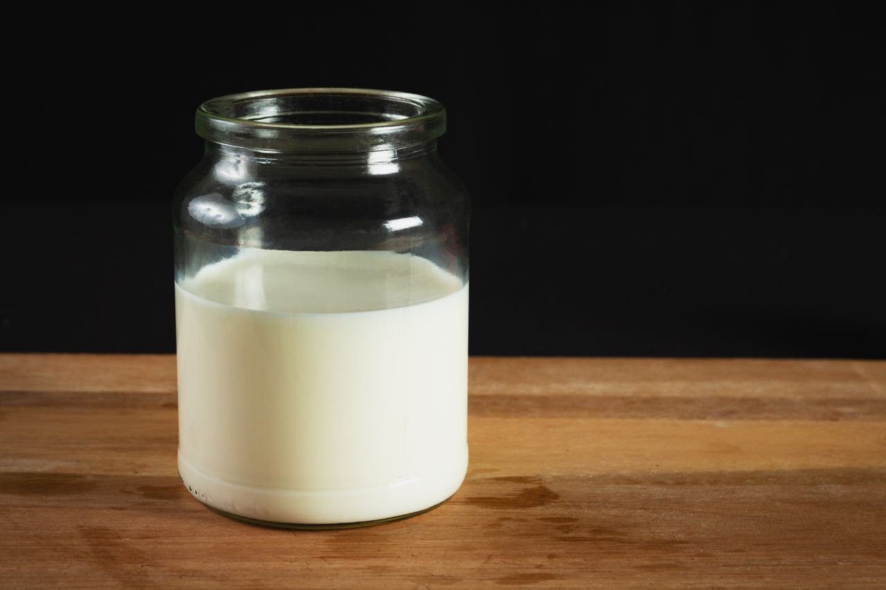 Palm Based Products & Cooking Oils A glass jar filled with milk on a wooden surface against a black background, perfect for dairy-related themes.
